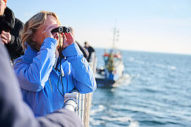 Steffi Lemke mit einem Fernglas auf einem Schiff. 