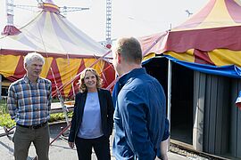 Bundesumweltministerin Steffi Lemke steht mit zwei Personen vor dem Cabuwazi-Kinderzirkus.