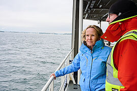 Steffi Lemke und ein Mann blicken auf einem Schiff in die Ferne. 