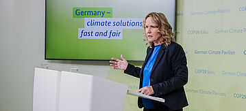 Steffi Lemke steht bei der COP29 in Baku im German Climate Pavilion am Rednerpult.